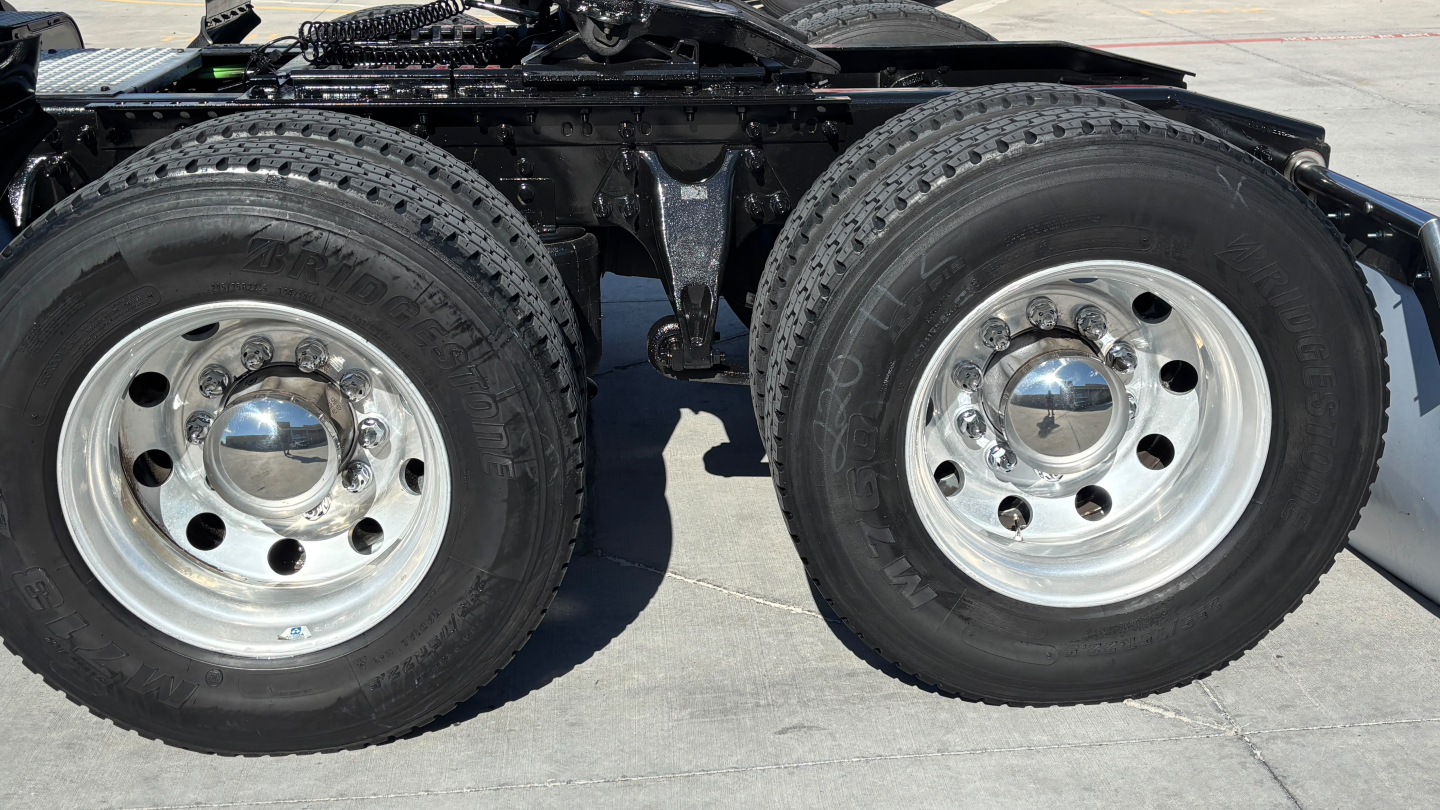 Dual rear truck wheels and suspension undercarriage showing chrome hubcaps and tires on a 2021 International LT625 truck.