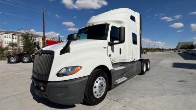 Truck cab side view of 2021 International LT625 conventional sleeper showing white cab, aerodynamic mirrors, and dual rear axles.