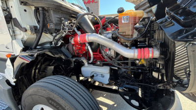 Truck engine bay showing intercooler pipes, hoses, and engine components of a 2021 International LT625 under the hood.