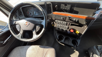 Truck interior dashboard with steering wheel, control panel, and center console showing gauges and multiple switches.