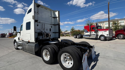 Tractor truck cab and rear chassis view showing fifth wheel and dual rear axles, International LT625 style sleeper highlighted in a truck yard.
