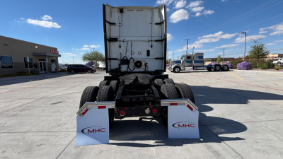 Rear view of a used semi truck tractor with dual rear axles and white MHC mud flaps.
