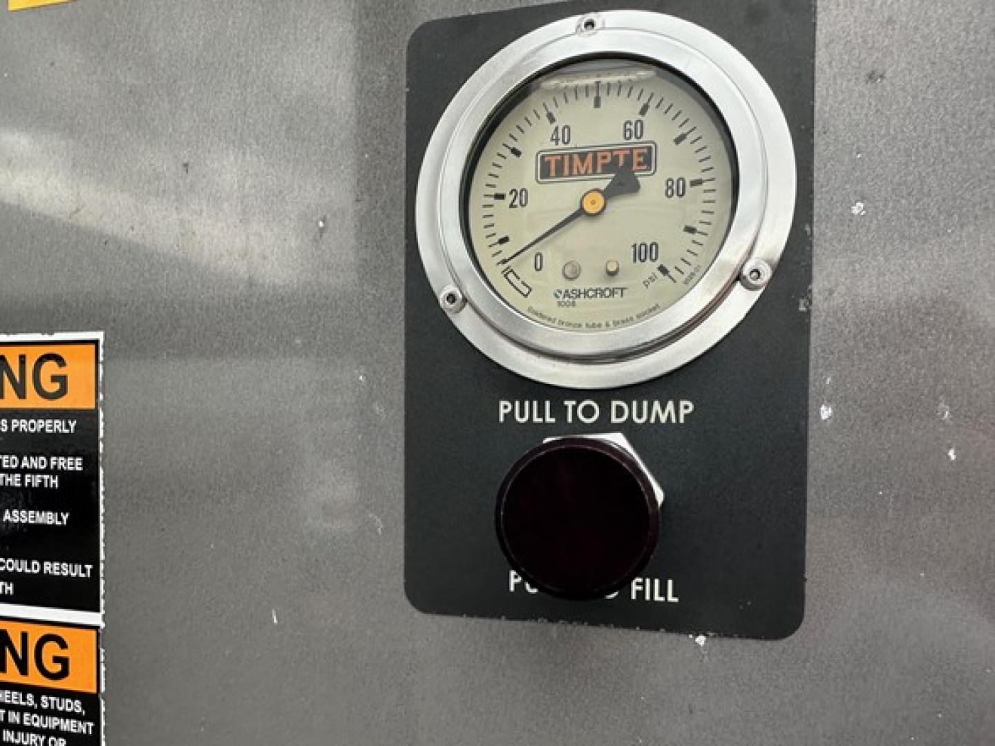 Timpte Super Hopper control panel with round gauge reading 0-100, label 'PULL TO DUMP' and circular fill cap.