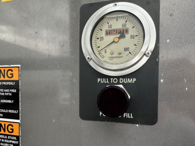 Timpte Super Hopper control panel with round gauge reading 0-100, label 'PULL TO DUMP' and circular fill cap.