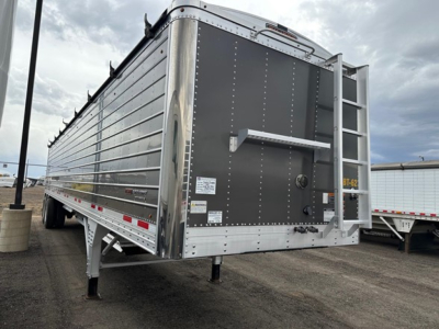 Trailer rear with vertical riveted metal sides of a 2024 Timpte Super Hopper, rear hatch and ladder visible, stock/ID plates and warning decals on tailgate.