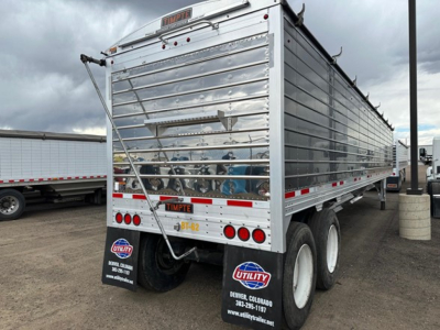 Trailer rear view showing 2024 Timpte Super Hopper with metal siderails and dual rear axles, utility decals and license plate area.