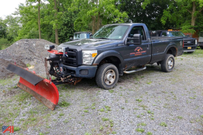 Ford F-250 Super Duty pickup with plow attachment in a gravel lot, utility truck with snow plow ready for use.