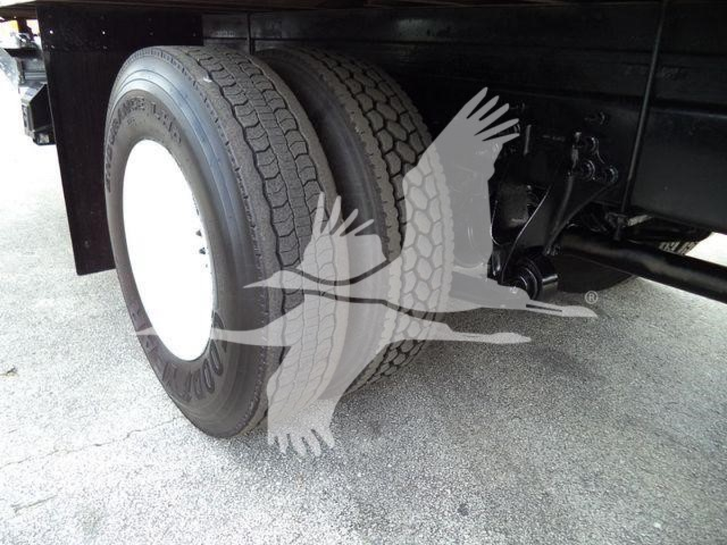 Truck dual rear wheels and suspension undercarriage visible, with white wheel rims and tire treads in view.
