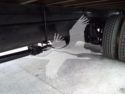 Truck undercarriage showing frame rails and a rear wheel on a box truck.