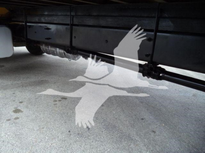 Underbody view of a 2019 International Durastar 4300 truck showing a hydraulic line and chassis with light spill on concrete.