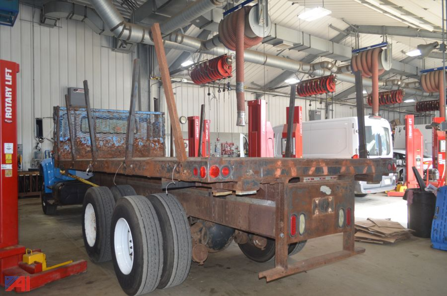 1992 International 4900 flatbed truck chassis inside a workshop with red equipment and hanging hoses.