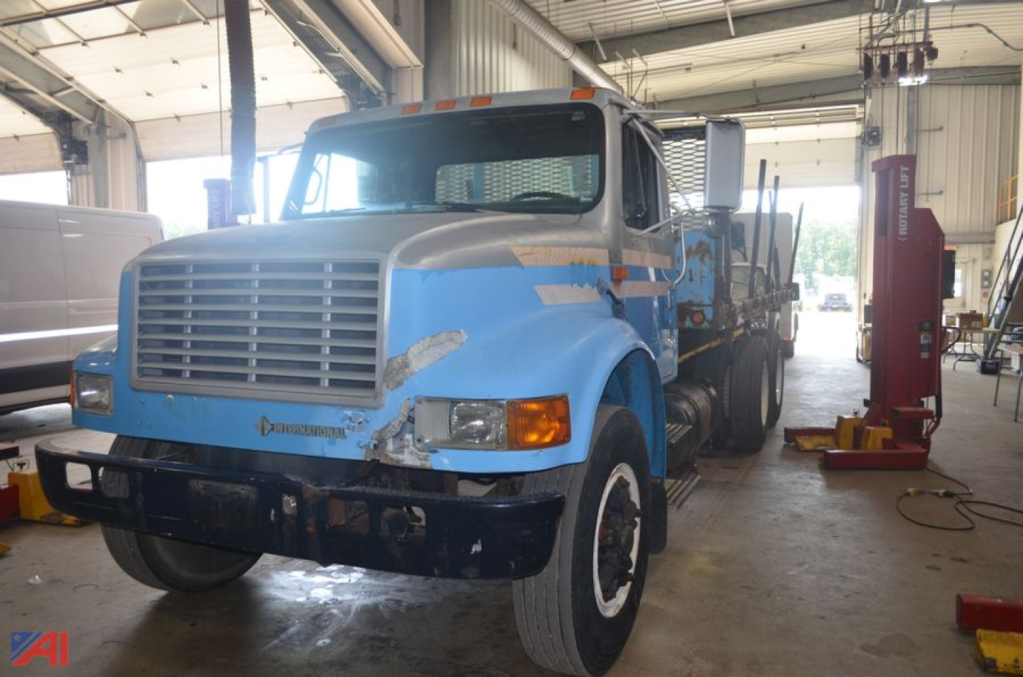 International 4900 flatbed truck in a workshop with blue paint and cargo bed.