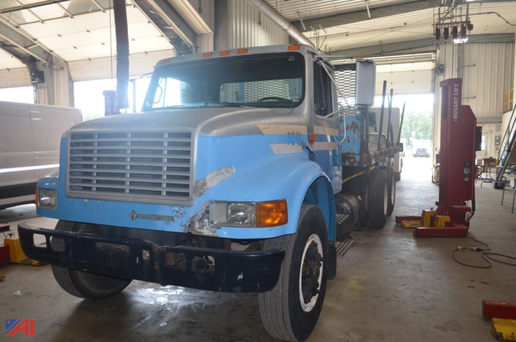 International 4900 flatbed truck in a workshop with blue paint and cargo bed.