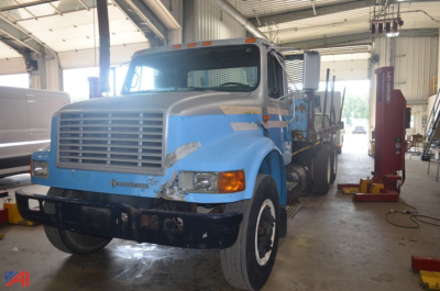 International 4900 flatbed truck in a workshop with blue paint and cargo bed.