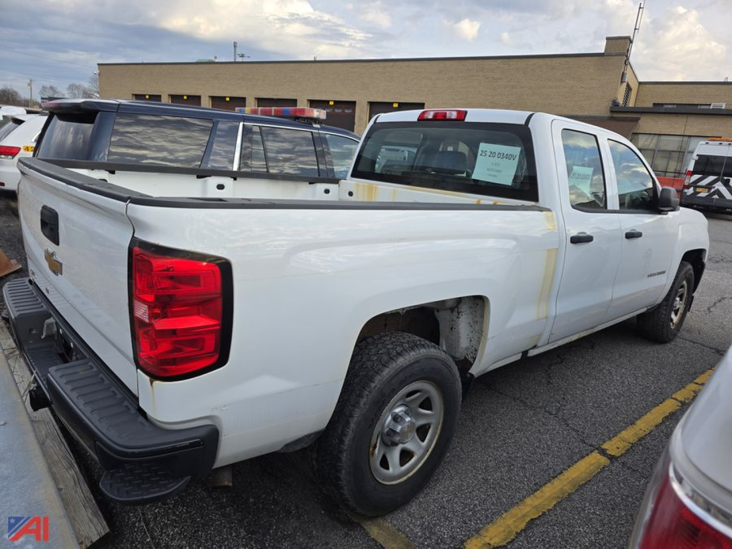 2017 Chevrolet Silverado 1500 pickup truck rear-side view in a parking lot. Visible text includes a sticker on the rear passenger window with vehicle details and a Chevrolet bowtie badge on the tailgate.