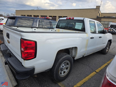 2017 Chevrolet Silverado 1500 pickup truck rear-side view in a parking lot. Visible text includes a sticker on the rear passenger window with vehicle details and a Chevrolet bowtie badge on the tailgate.