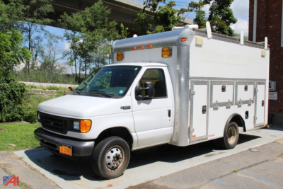 Box truck with utility compartments and Ford E-Series chassis in a parking lot