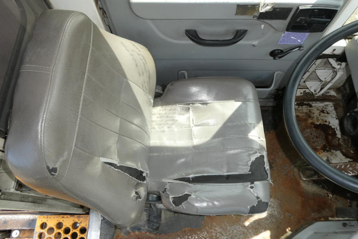 Interior of a 2013 Kalmar Ottawa YT30 cab showing a damaged driver's seat and worn steering wheel.