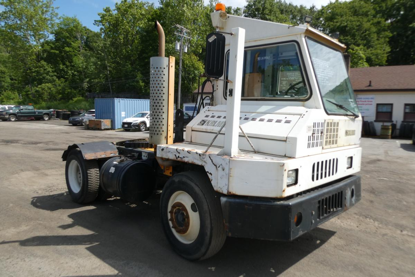 Kalmar Ottawa YT30 yard truck showing cab and chassis with white paint and worn body, exhaust stack, and dual rear wheels.
