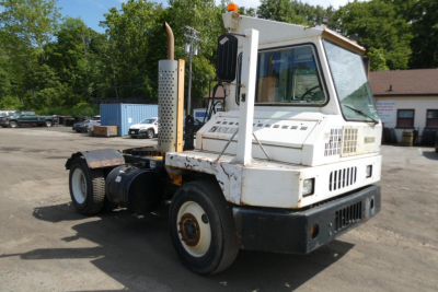Kalmar Ottawa YT30 yard truck showing cab and chassis with white paint and worn body, exhaust stack, and dual rear wheels.