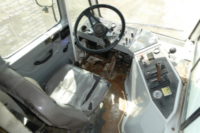 Cab interior of a used Kalmar Ottawa YT30 yard truck showing steering wheel, control panel, and worn seat with some rust and dirt on the floor.