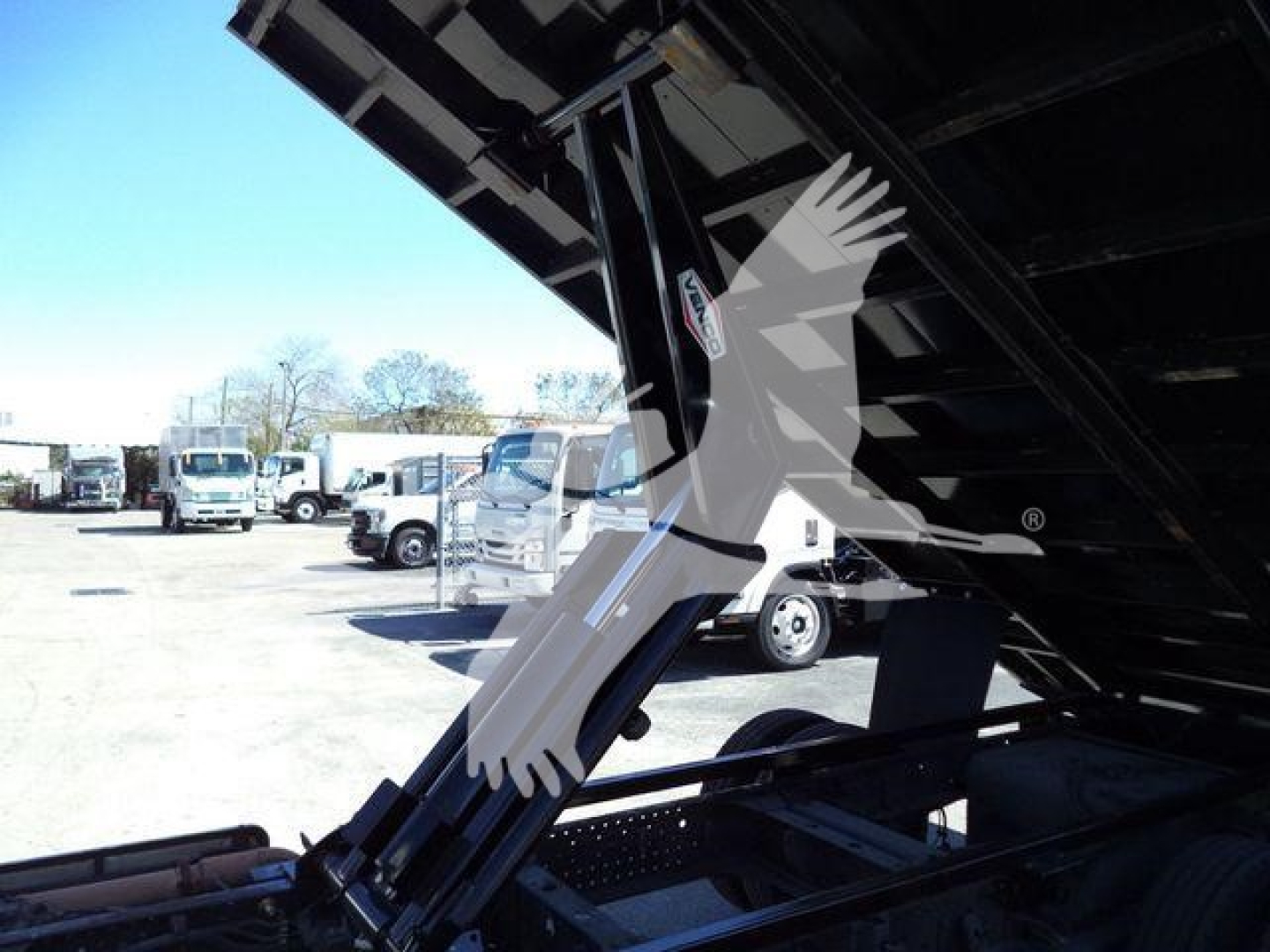 Isuzu NPR-HD dump truck bed support arm visible under raised bed