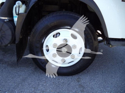 Isuzu NPR HD wheel and front fender showing front wheel with white hubcap and tire, part of dump truck undercarriage