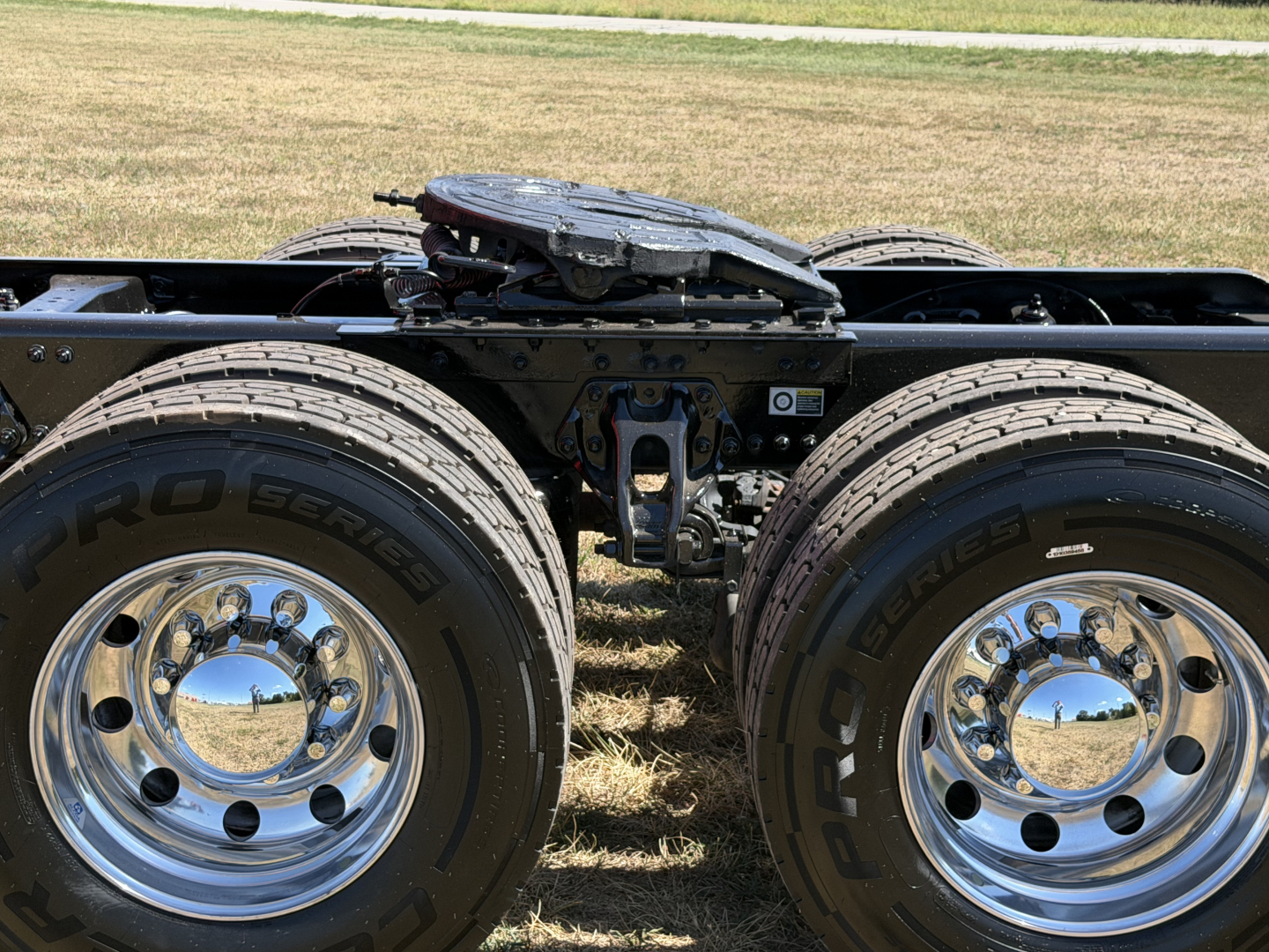 Kenworth T680 chassis with dual rear axles and chrome wheels showing the fifth wheel hitch and frame detail.