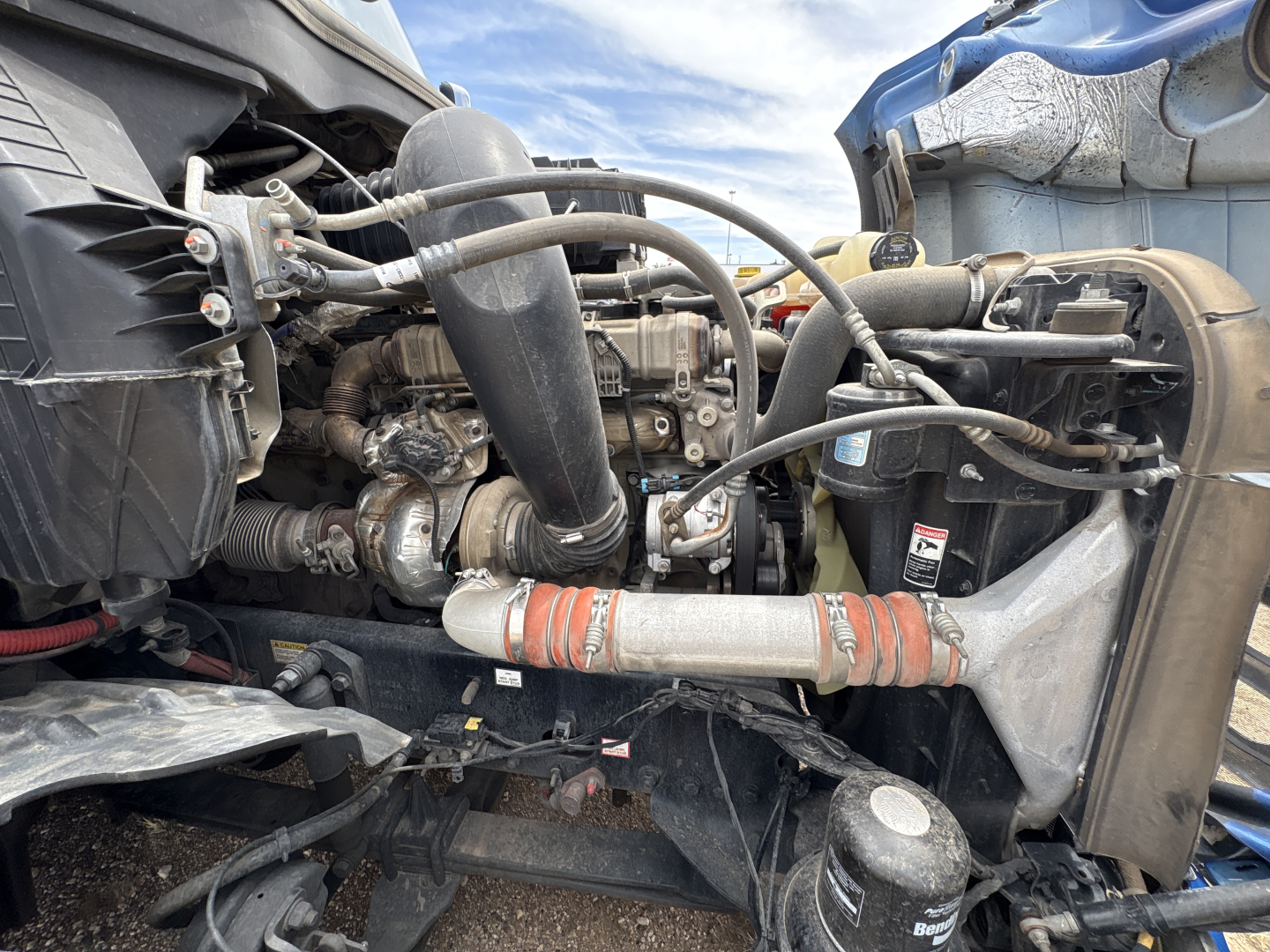 Freightliner Cascadia 126 engine bay with hoses, intercooler, radiator, and turbo piping visible.