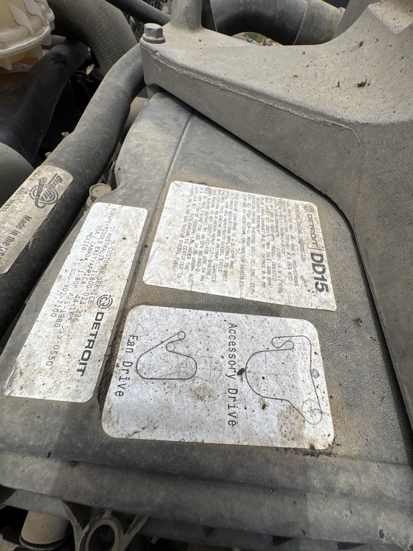 Crew cab engine bay label panels with safety and fluid labels including 'DEFERTOF' and 'Accessory Drive' near the top of a Freightliner Cascadia engine bay.