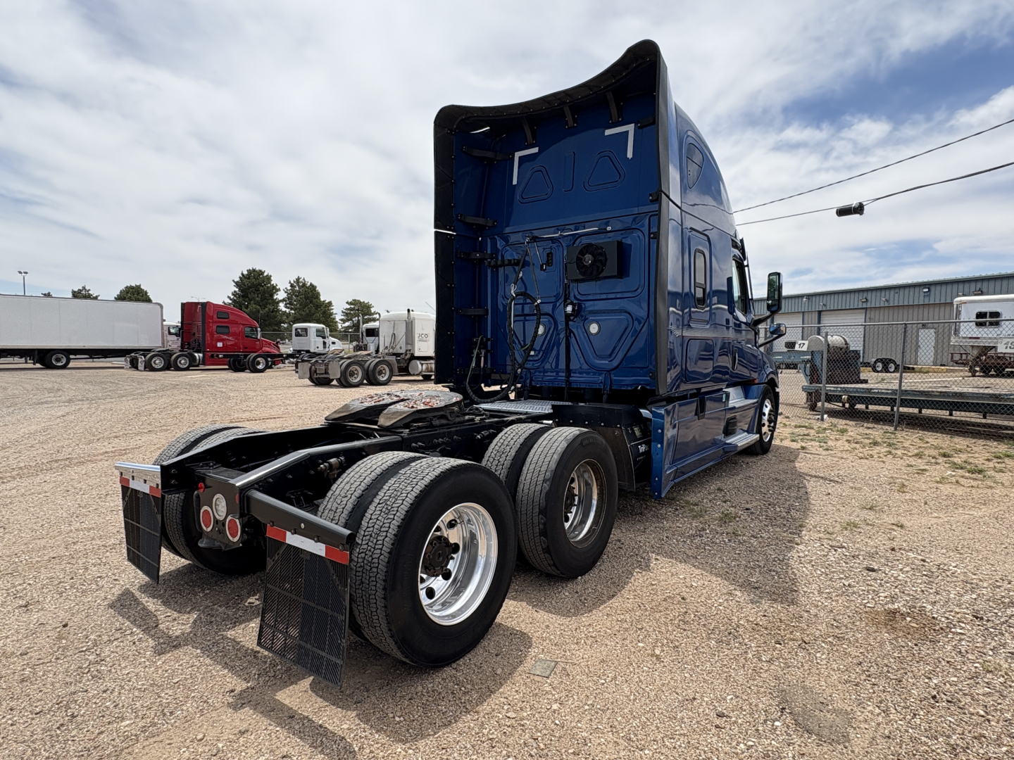 Truck rear view of a blue 2022 Freightliner Cascadia 126 semi tractor showing dual rear axles and fifth wheel hitch setup.