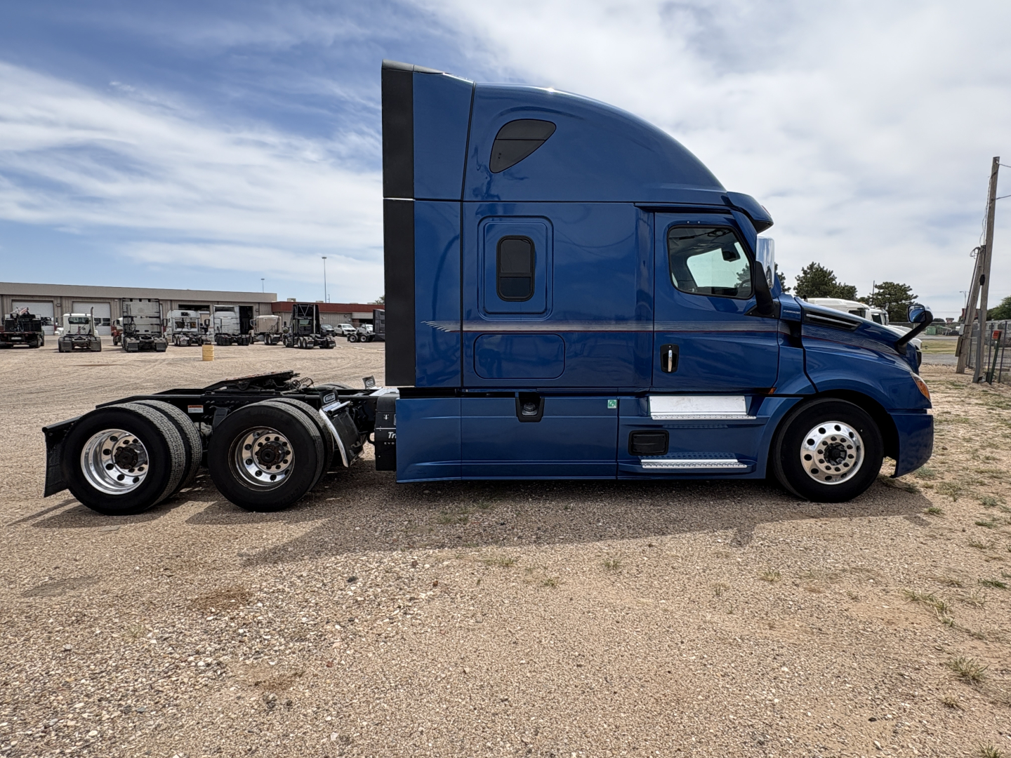 Blue 2022 Freightliner Cascadia 126 tractor-trailer side view showing sleeper cab and rear wheels
