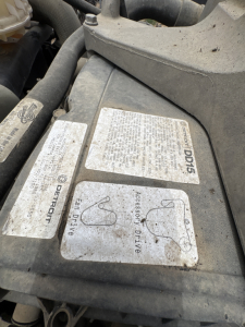 Crew cab engine bay label panels with safety and fluid labels including 'DEFERTOF' and 'Accessory Drive' near the top of a Freightliner Cascadia engine bay.