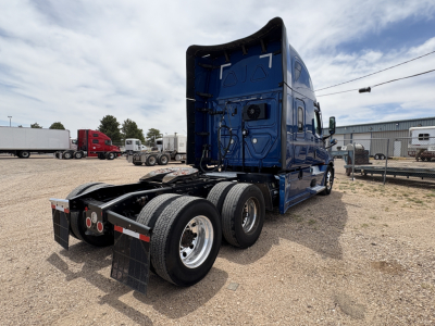 Truck rear view of a blue 2022 Freightliner Cascadia 126 semi tractor showing dual rear axles and fifth wheel hitch setup.