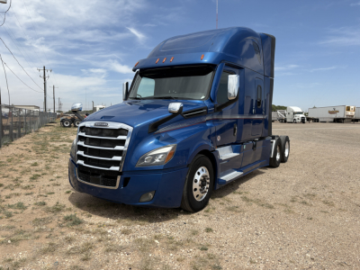 Truck image: blue 2022 Freightliner Cascadia 126 sleeper cab, front-left view showing grille, headlights, and side profile on a gravel lot.