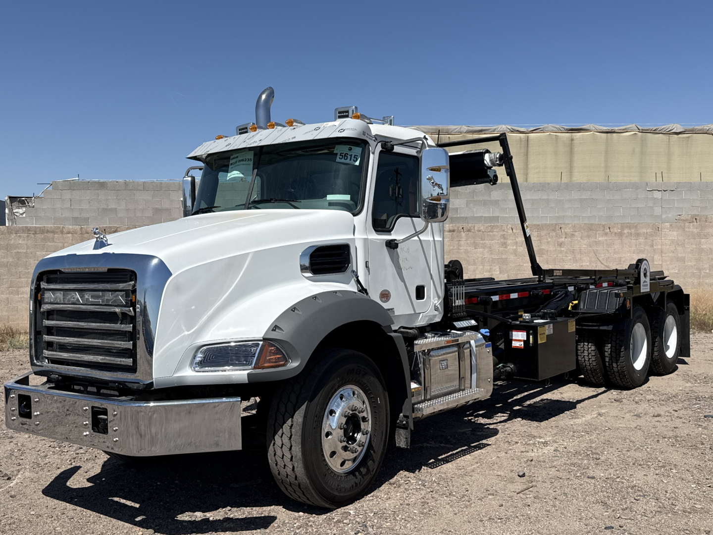 Mack GR64B roll-off truck side view showing cab and chassis with rear hoist and empty roll-off bed.