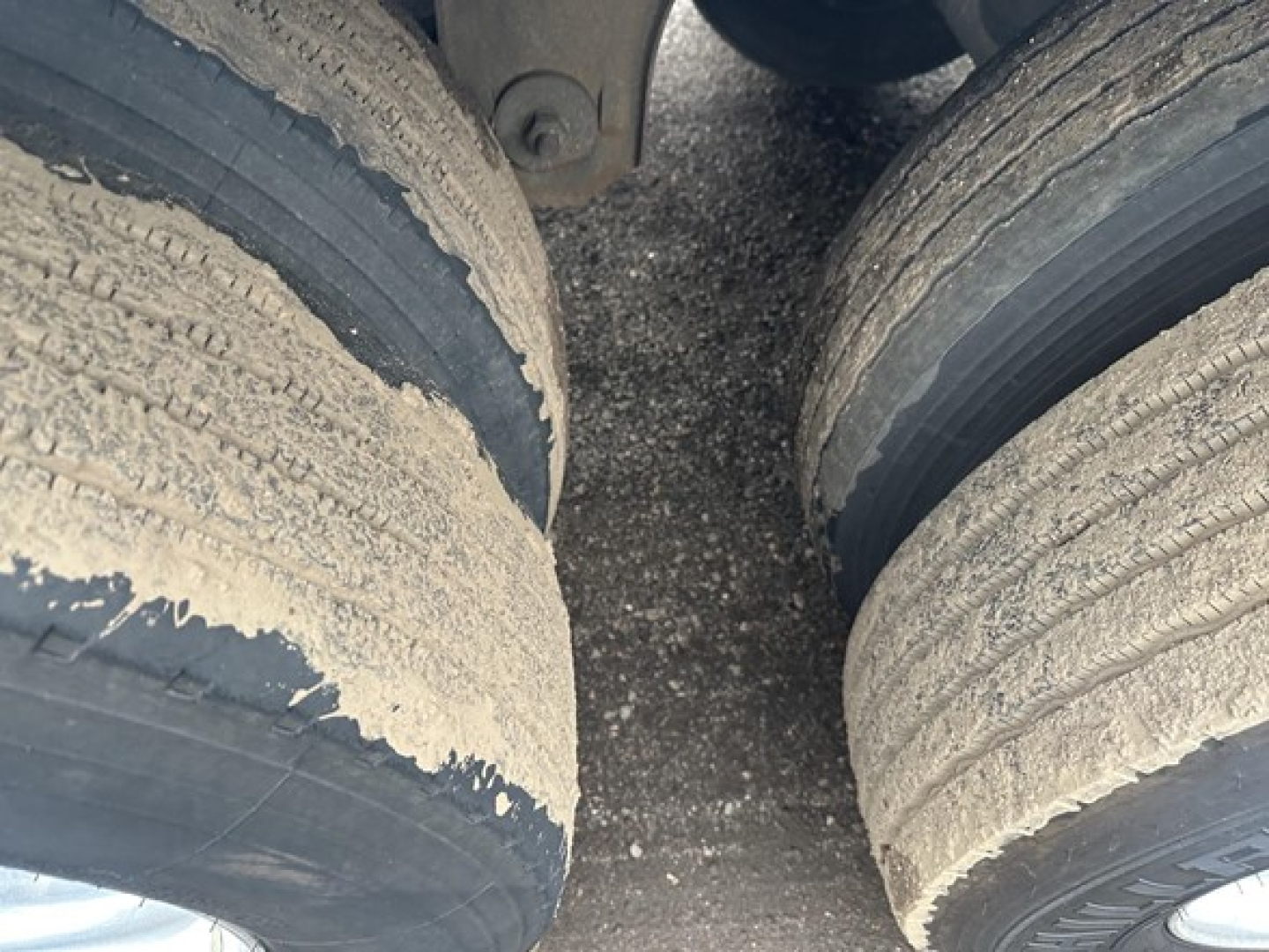 Trailer axles and dual tires with worn tread and dirt buildup visible between wheels.