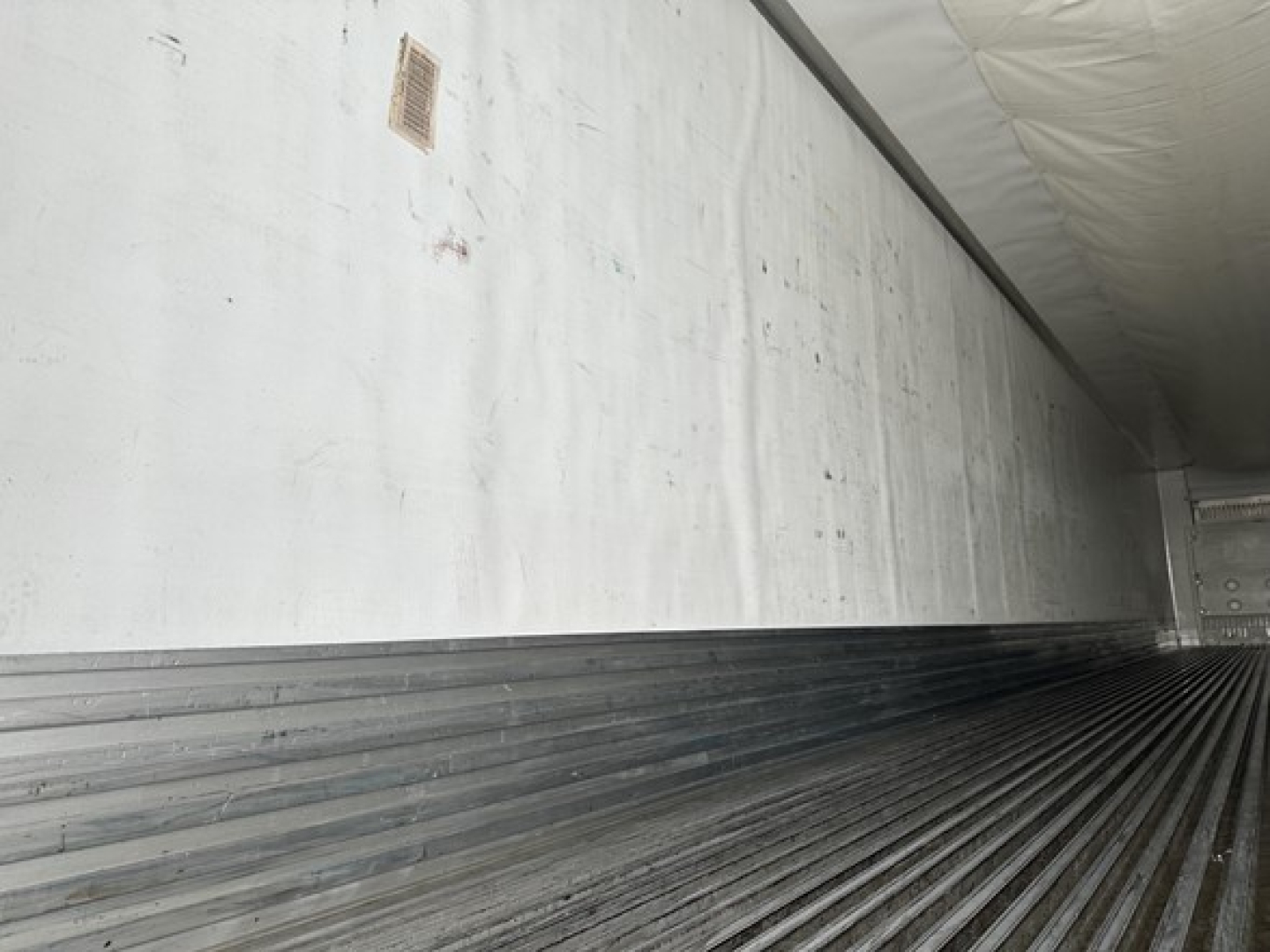 Rear interior of a Utility 3000R trailer cargo area with insulated white walls and ribbed steel floor.