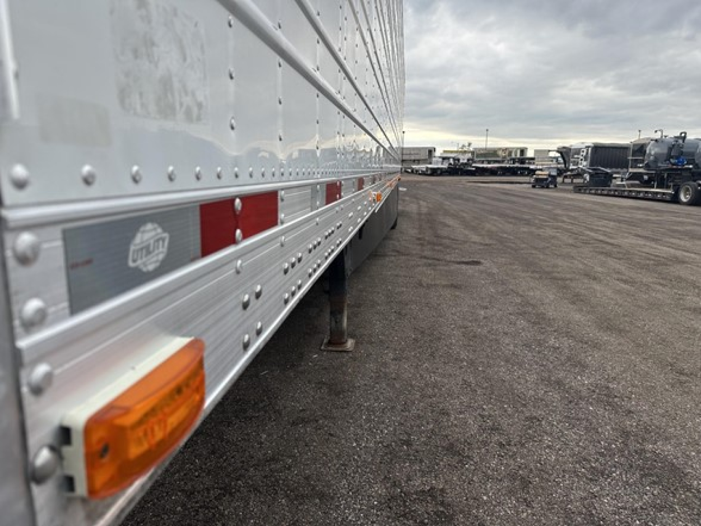 Utility trailer side view showing reflective tape and stabilizer leg with orange marker light