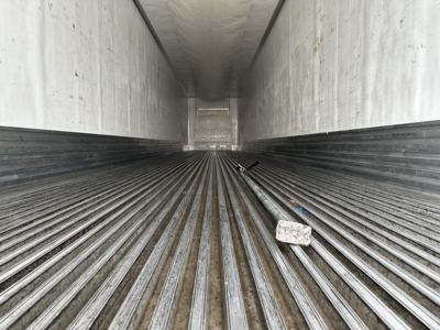Interior of a Utility 3000R trailer cargo area with ribbed floor and rear door, showing metal walls and a few scattered objects.
