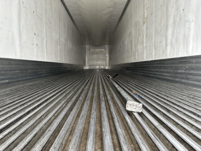 Trailer interior showing ribbed metal floor in a refrigerated trailer with light at far end and a small block on the floor.