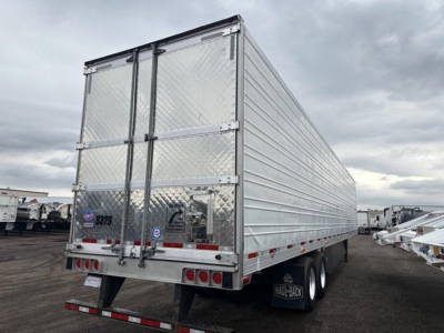 rear of a silver Utility 3000R trailer with doubled doors, diamond plate panels, and trailing undercarriage; rear bumper with lights; various stickers on left door.