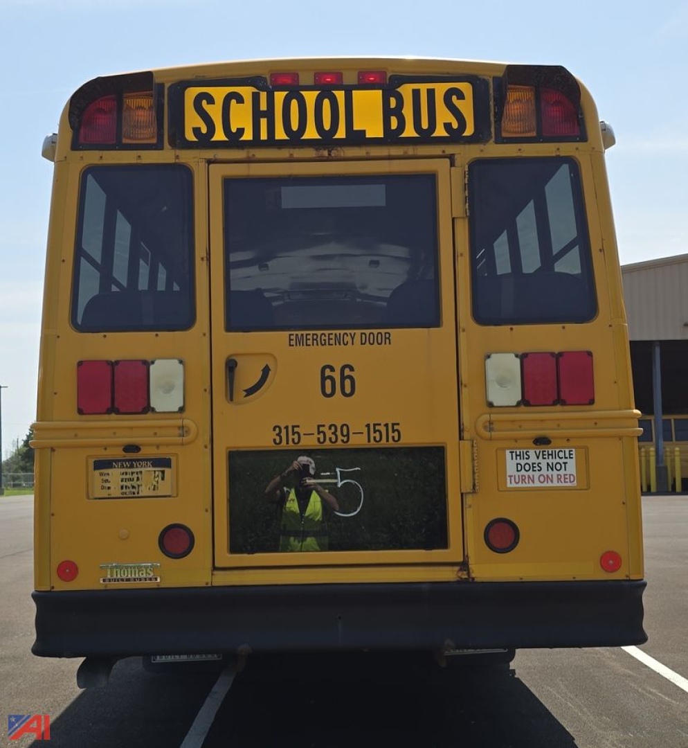 Rear view of a yellow school bus with 'SCHOOL BUS' sign, emergency door, bus number 66, phone number, and warning stickers.