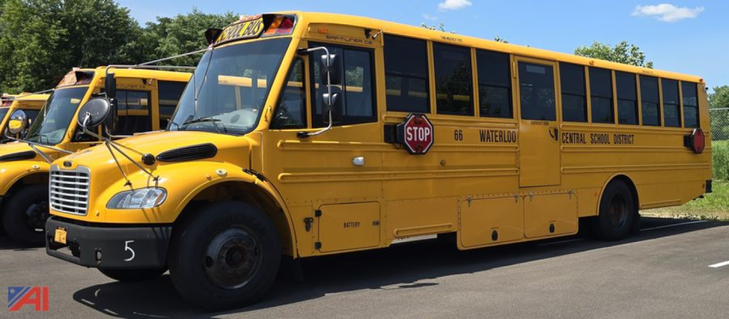 Yellow Freightliner Thomas bus showing stop sign, school bus exterior with black tires and reflective markings.