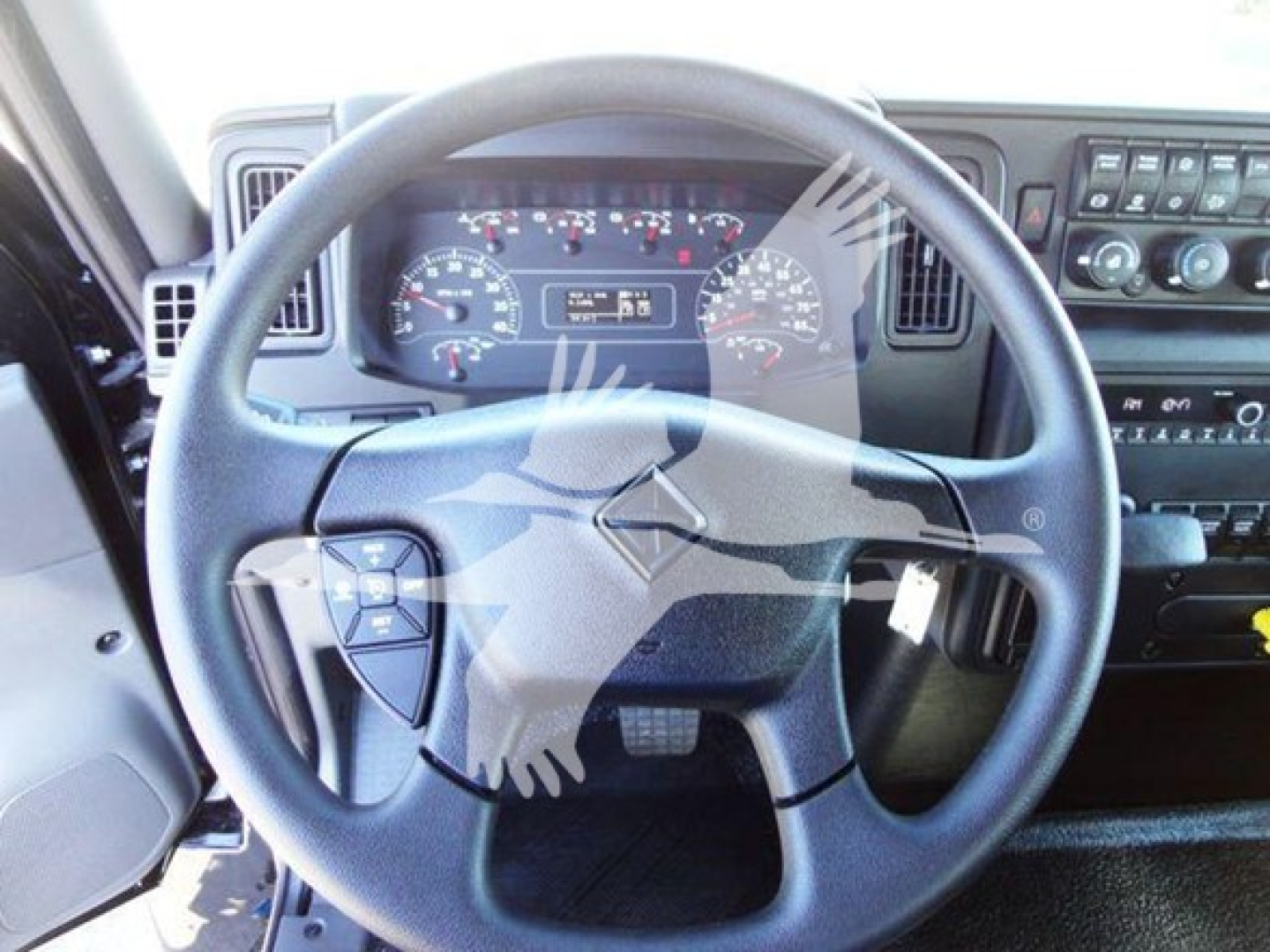 Truck cab interior showing steering wheel and dashboard of a 2022 International MV rollback truck with gauges and controls visible.