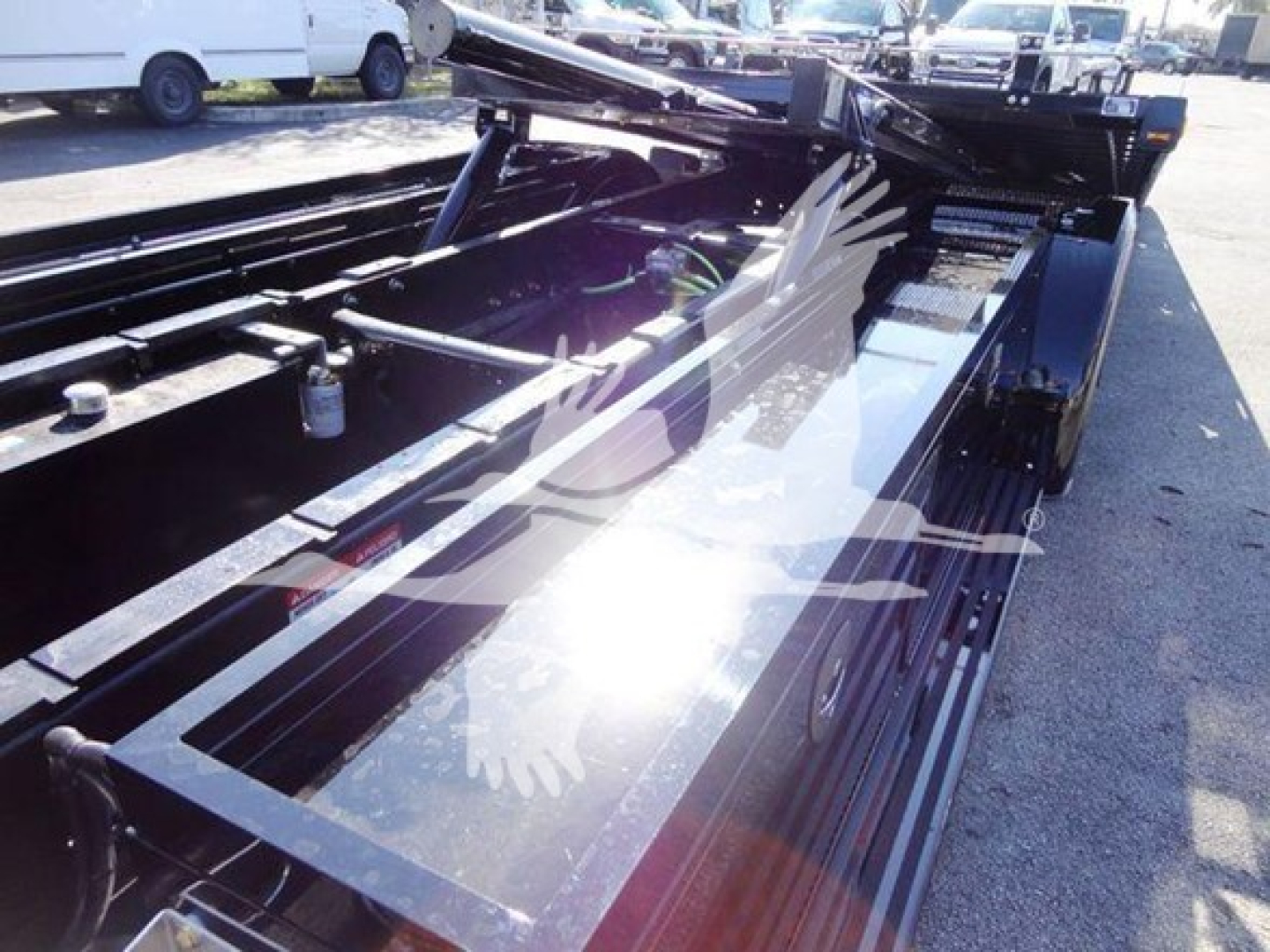 Tow truck rollback bed with hydraulic components and metal frame showing storage side rails and controls.
