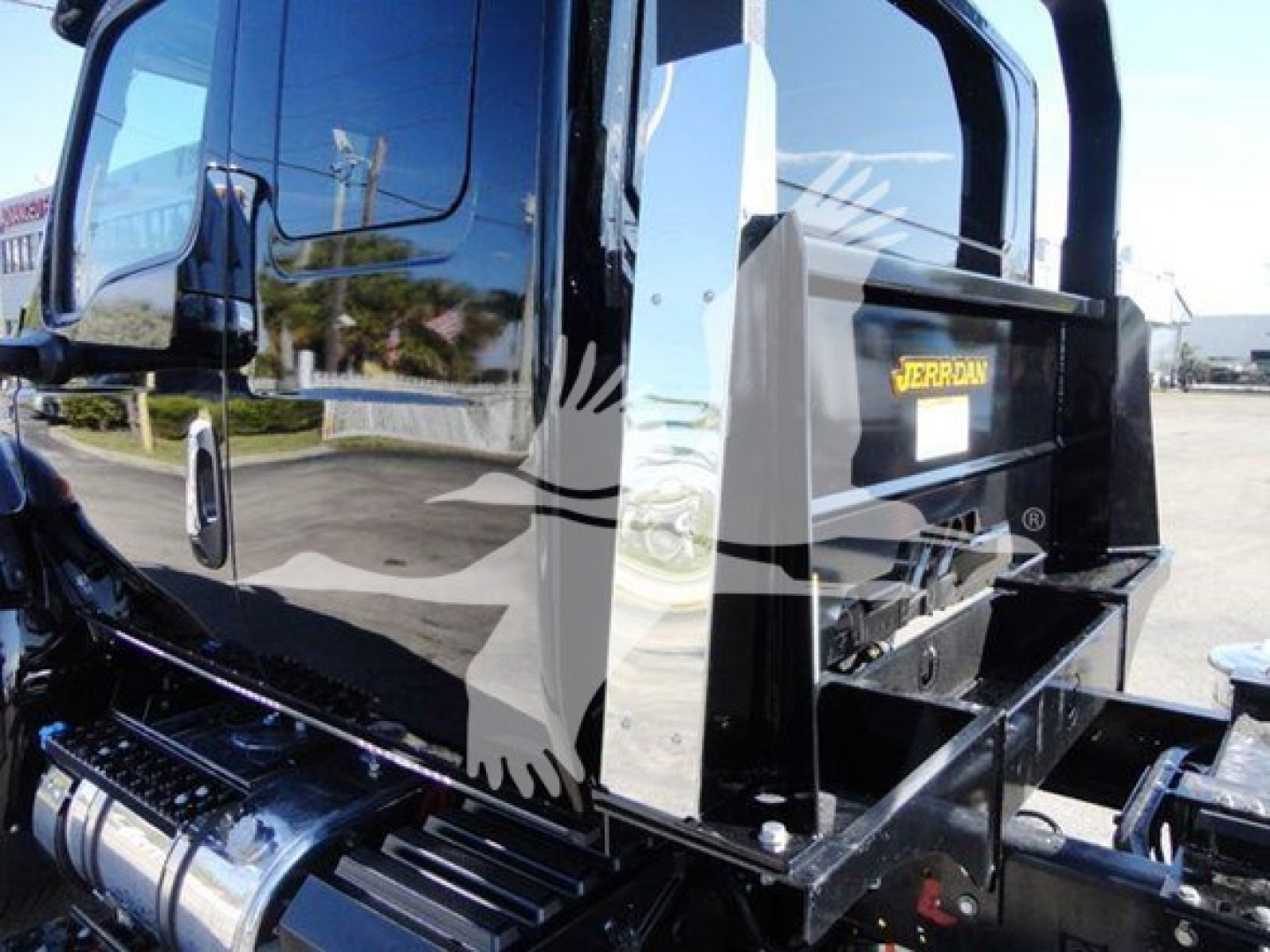 Truck cab and rollback bed of a new 2022 International MV showing chrome fuel tank and black equipment box with JERR-DAN label.