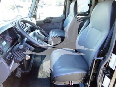 Truck cab interior showing driver's seat and steering wheel of a 2022 International MV with light gray seats and dashboard controls.