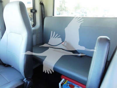 Truck interior showing front seat and bench seat in blue upholstery; cab area with windows and door; no visible branding text.