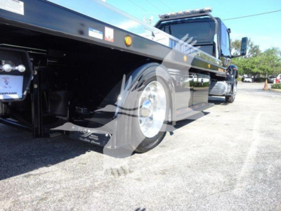 Flatbed tow truck chassis and rear wheel view showing 2022 International MV with aluminum flatbed and tandem axle, side decals, and reflective markings.